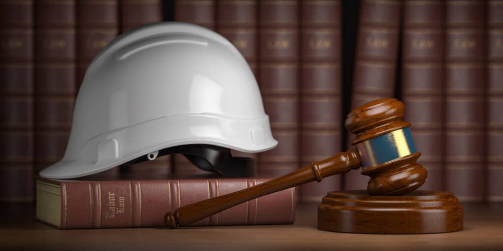 Labor law concept. Gavel with concstruction hard hat and books.