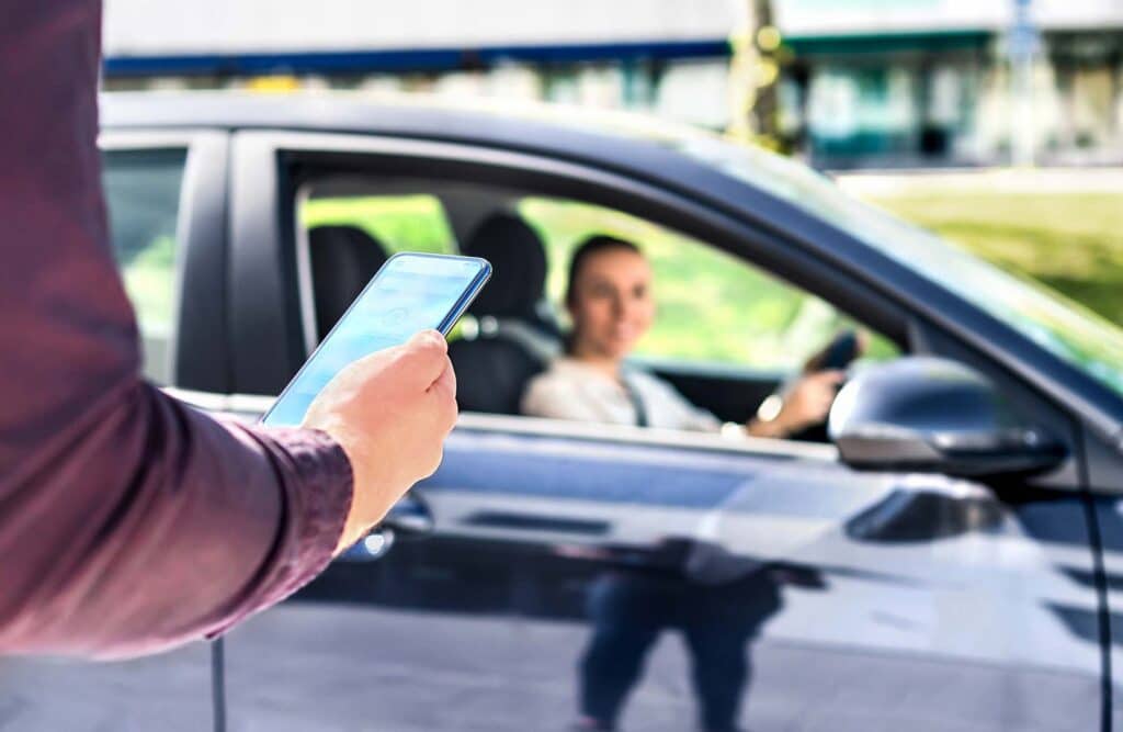 A rideshare driver arriving to pick up a customer who used an app on their smartphone to order a ride.