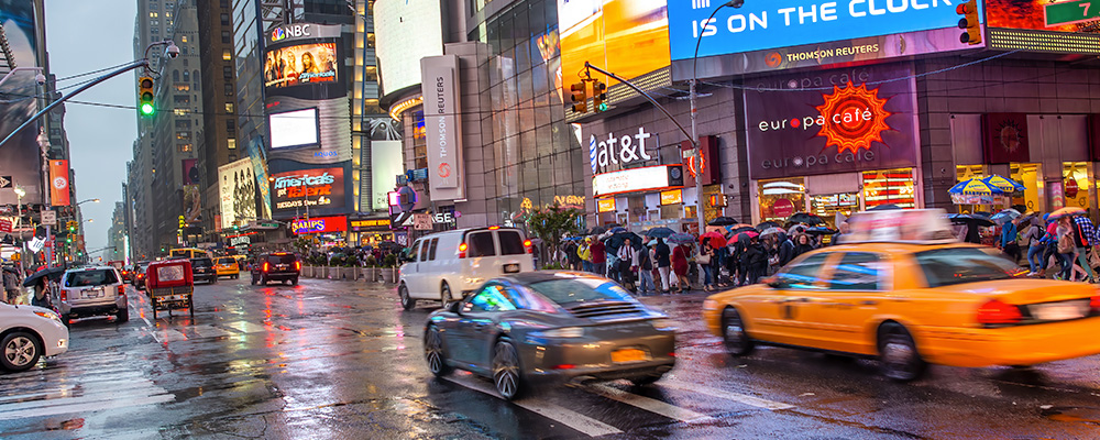 Traffic and pedestrians moving through a busy intersection in New York City.