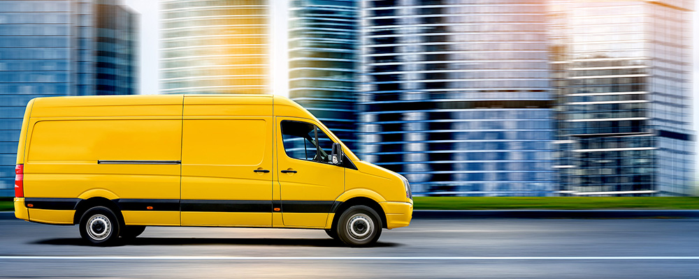 Commercial delivery van traveling through an urban roadway environment.